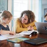 Mother and children with laptop learning at home and smiling.