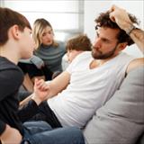 father looking stressed while talking to his young son