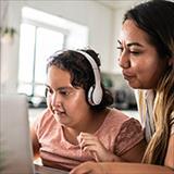 Young girl with autism participates in an online research study assisted by her mother.