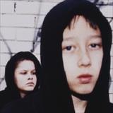young men in dark hoodies standing by spraypainted wall
