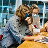 College students wearing face masks working together in computer lab