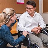 Therapist works with man in wheelchair who has Down syndrome.