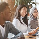 African American student, Asian student, and student wearing a hijab sit together at a table.