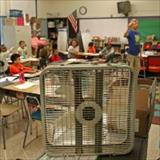 This image shows a box fan positioned at the front of a classroom to improve ventilation