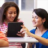 Teacher assists students using tablet.