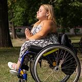 Young woman meditates while sitting in her wheelchair.