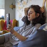 A girl sitting on her bed and staring at her phone
