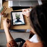 An artist sitting at her desk drawing a picture on her tablet device