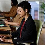 A woman working at a desk in a workplace setting.