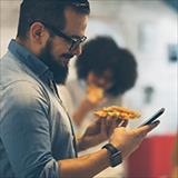 Man looking at his phone and holding a slice of pizza