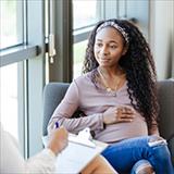 Expectant young woman listens to unrecognizable female counselor