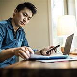 Man with phone looking at manual