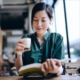 Woman reading while holding a cup of coffee