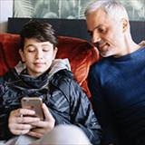 Father and young teen son looking at smartphone