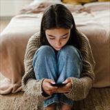 Teenage girl sitting on the floor and scrolling her smartphone