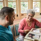 Senior woman and mid adult nurse looking at photo album in the dining room in a nursing home