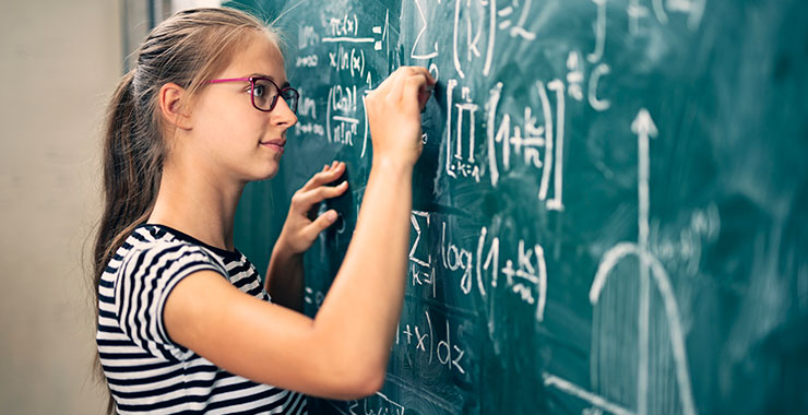 teen girl solving advanced math problems at blackboard