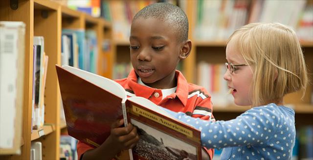 elementary school students looking at a book