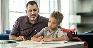 Father with son looking over homework and writing.