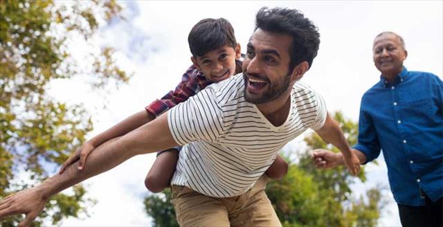 father giving son a piggyback ride while grandfather watches
