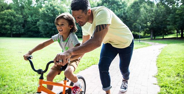 father teaching his son how to ride a bike