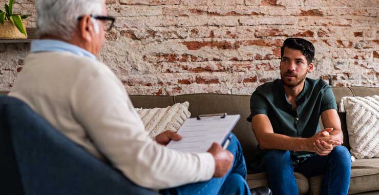 A licensed therapist is listening to and taking notes while a patient shares their experiences
