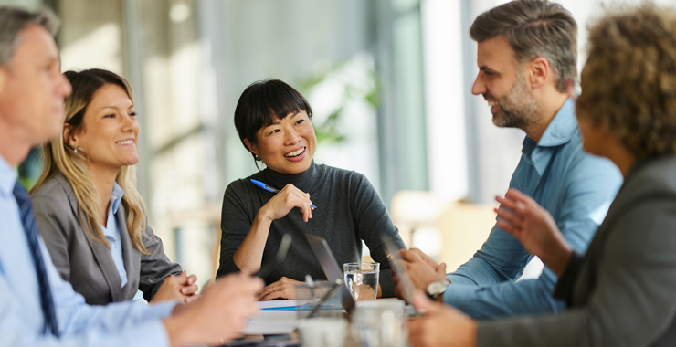 Young professionals sitting around a table speaking to each other.