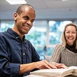 two people seated at a table looking through books