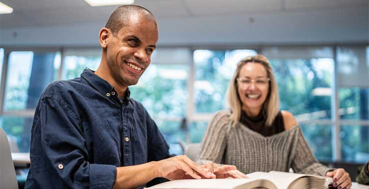 two people seated at a table looking through books