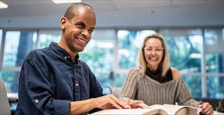 two people seated at a table looking through books