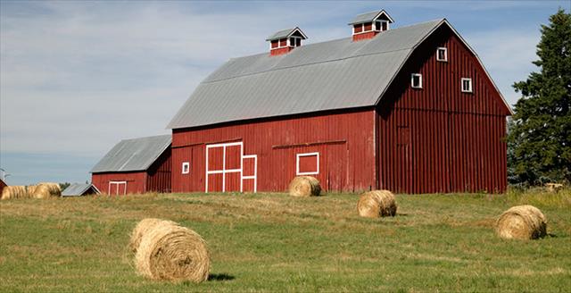 red barn with hay bales in front