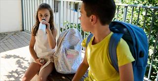 two children sitting on bench outside school building