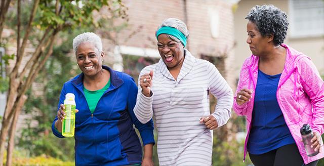 three Black women power-walking in a park