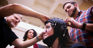 Dr. Strayer helps place an electroencephalogram (EEG) cap on a study participant.