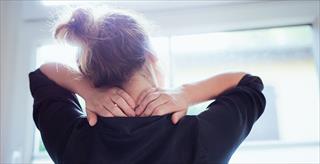 research on psychology topics woman rubbing the back of her neck and shoulders