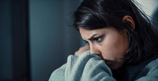 young female with depression sitting in a dark room
