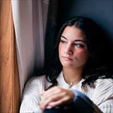 Young woman sitting near a window with a thoughtful and reflective expression