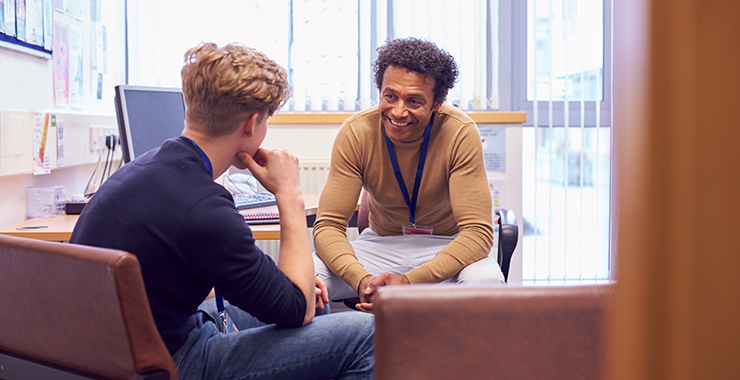 Two adults talking to each other in an office environment.