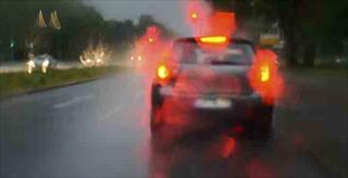 car showing third brake light in heavy traffic on wet road