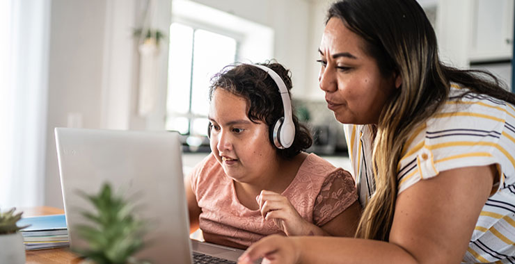 Young disabled girl using adaptive technology to attend class.