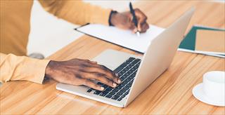 African-American man working on his laptop and writing
