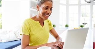 African-American woman using laptop in kitchen at home