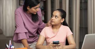 parent talking to teen who is holding a smartphone