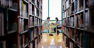 Young man and woman collaborating on an educational project in a peaceful university library