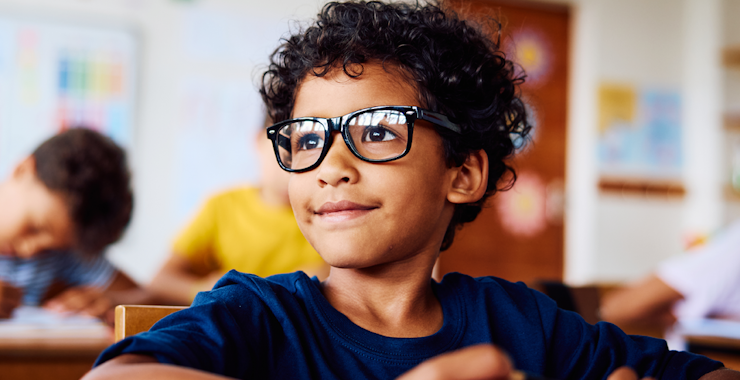 A young child with glasses in a classroom