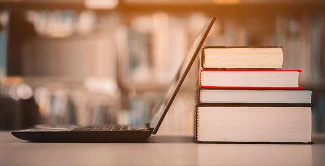 Open laptop propped up against a stack of books in the library.