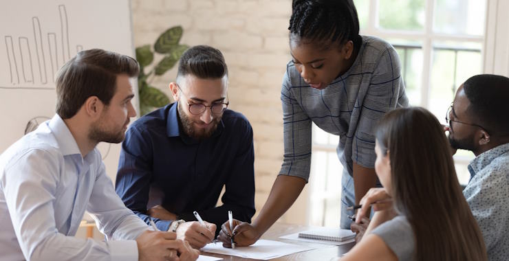 A group of coworkers siting around a conference table engaged in a meeting