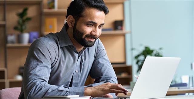 Young Indian man looks at laptop screen.