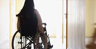 Young woman sits in wheelchair; her back is to the camera.