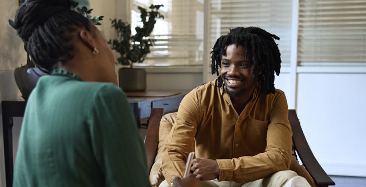 Two people engaged in a conversation during a counseling or therapy session in an office setting.